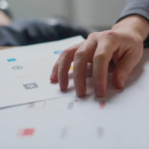 man reviewing multiple logo proposals